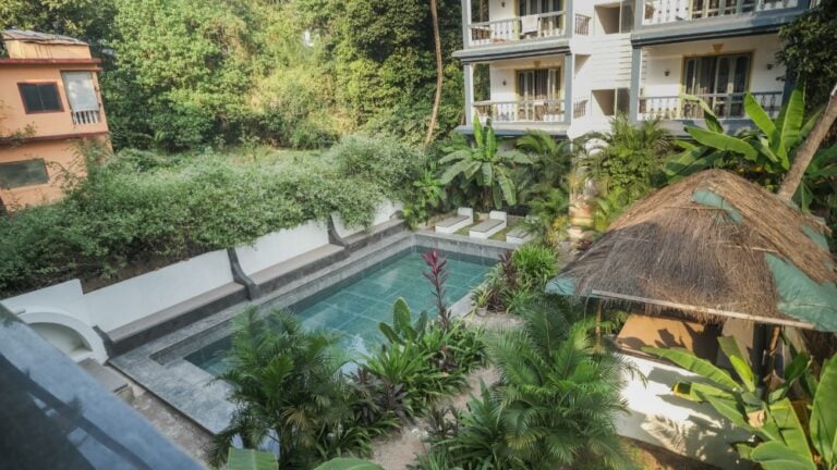 Photo du centre Nalanda montrant l'espace piscine niché dans la végétation, entre les bâtiments.