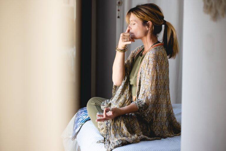 Photo de profil de Gwladys qui pratique les pranayamas, assise en tailleur sur son lit